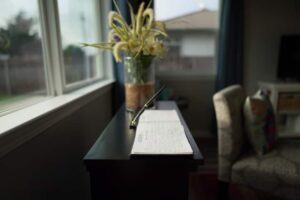 A console with a guest book and a flower vase on top
